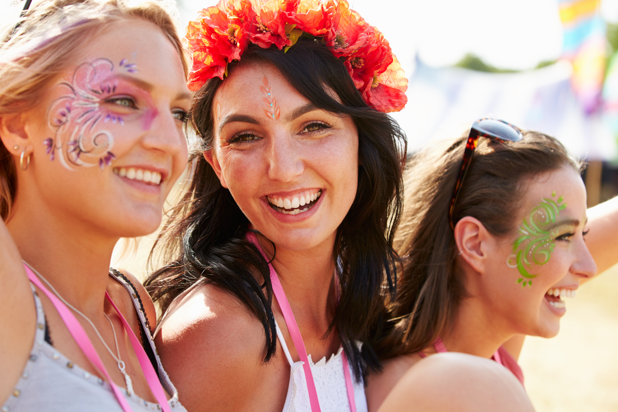Three girl friends at a music festival with face painting and makeup