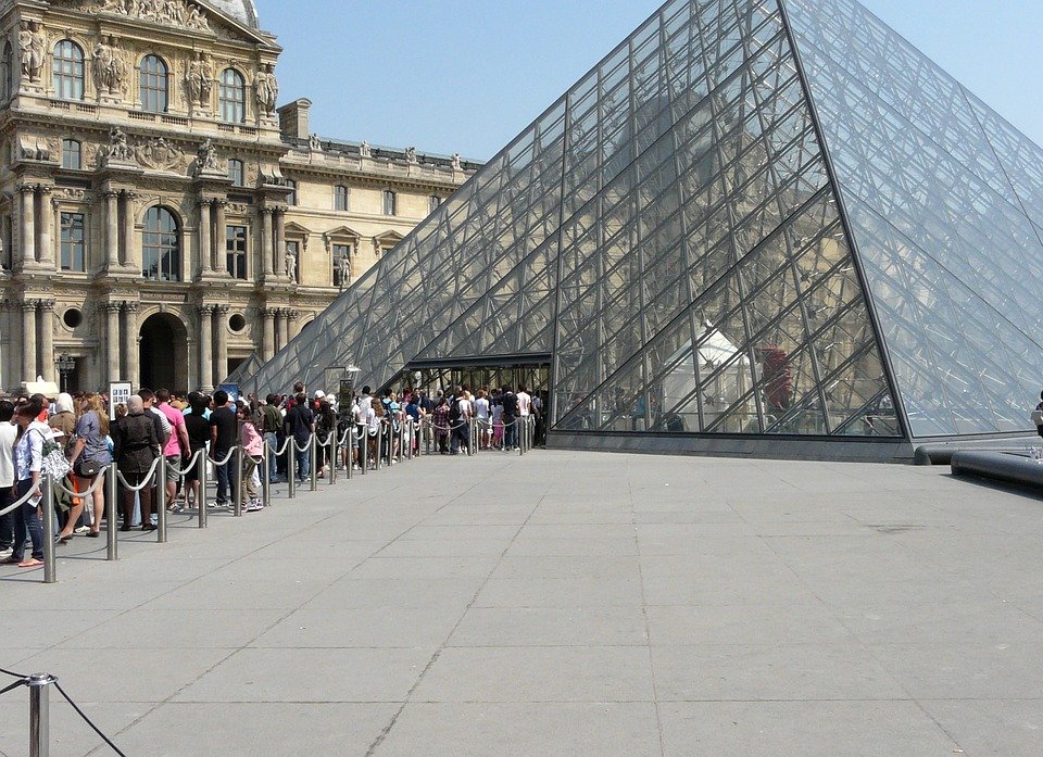 The Louvre Museum, with a long queue of visitors by the entrance of the pyramid