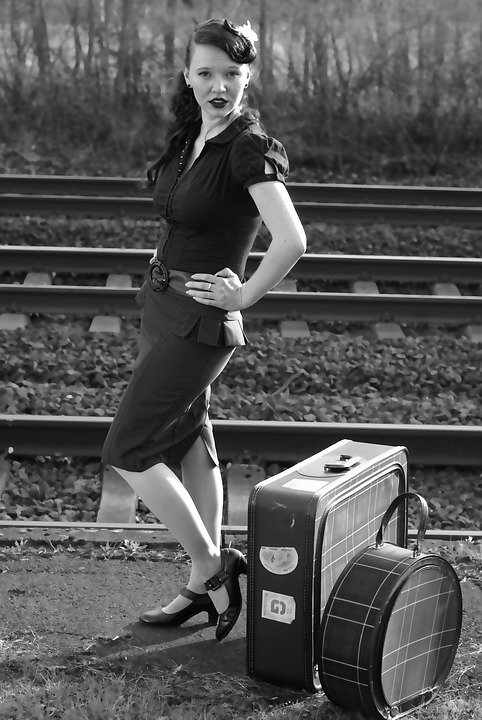 A well-dressed woman standing near the train tracks