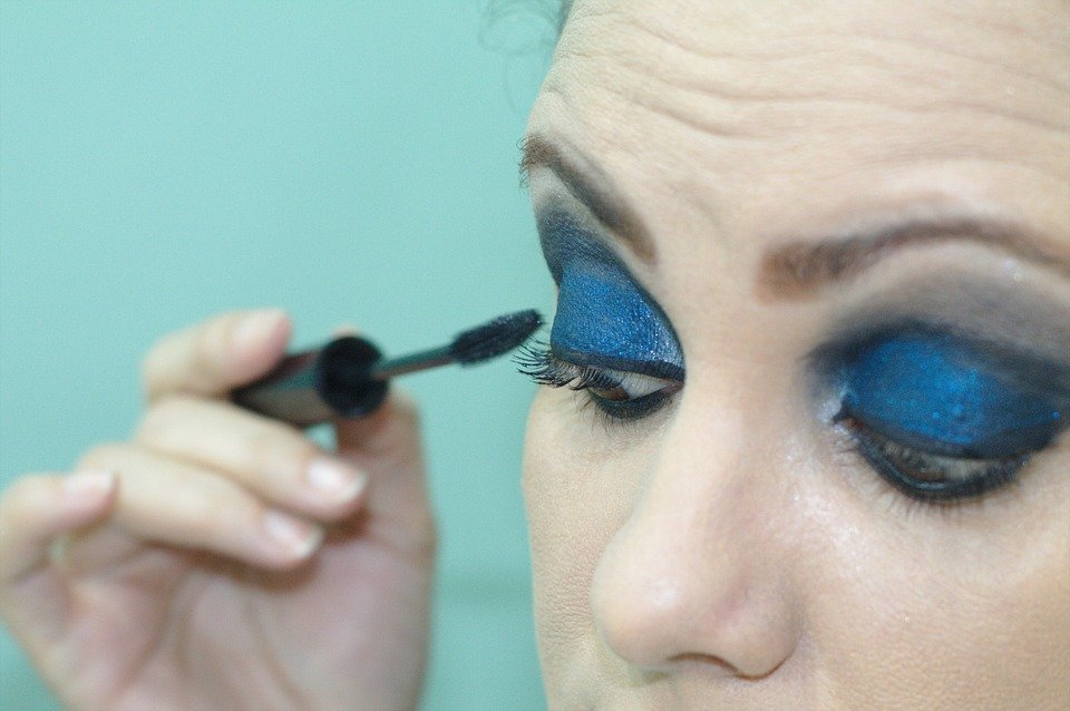 a woman applying makeup on her eyes