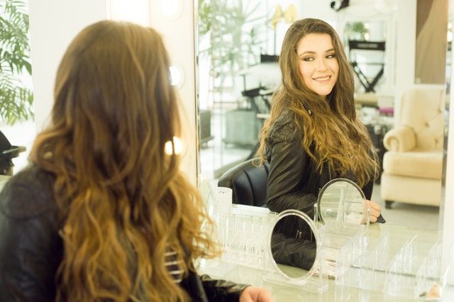 woman looking at the mirror in her well-lighted makeup studio