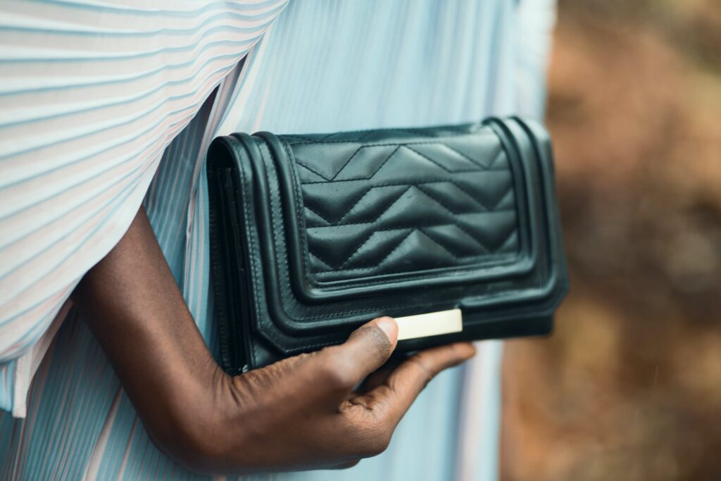person holding a black leather clutch