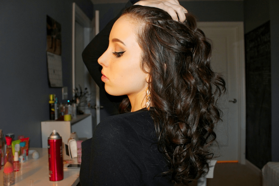 a side profile of a girl with long black curly hair and a black dress