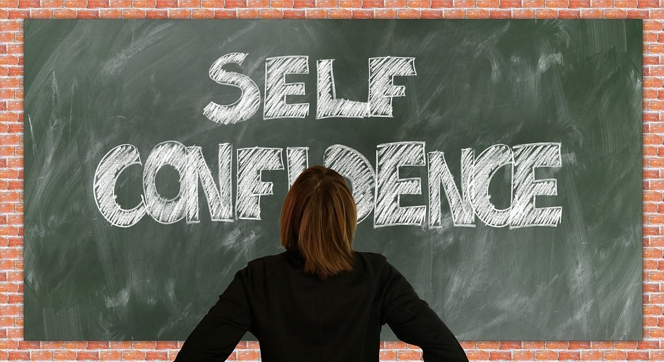 A lady staring at the board which has self-confidence written on it