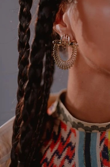 A closeup image of a woman wearing gold earrings