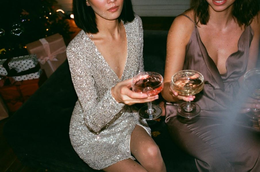 two women wearing bias cut dresses holding wine glasses