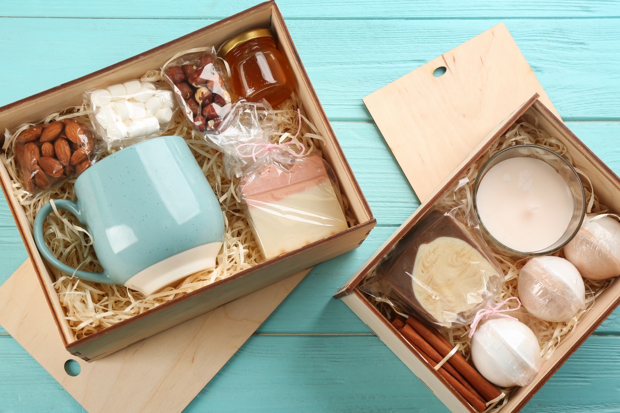 Boxes with stylish craft gift sets on light blue wooden table, flat lay